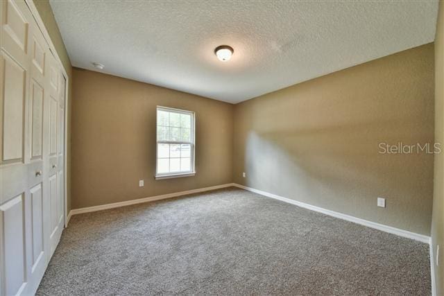 unfurnished bedroom featuring carpet, a textured ceiling, and a closet