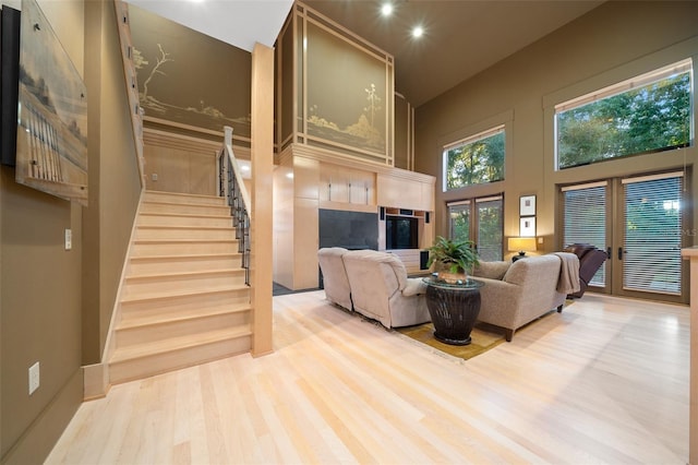 living room with french doors, light hardwood / wood-style floors, and a high ceiling