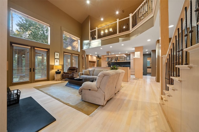 living room with light hardwood / wood-style floors, a high ceiling, and french doors