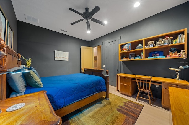 bedroom with ceiling fan, built in desk, and wood-type flooring