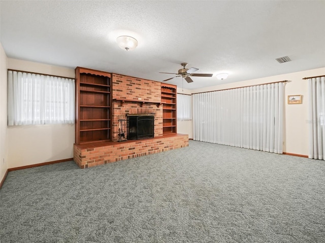 unfurnished living room featuring ceiling fan, a fireplace, carpet floors, and a textured ceiling