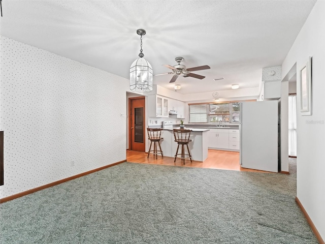 unfurnished living room with sink, light colored carpet, a textured ceiling, and a notable chandelier