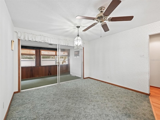 interior space featuring carpet flooring, a textured ceiling, and ceiling fan with notable chandelier