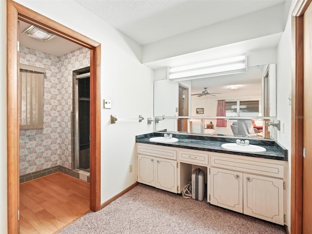 bathroom with a shower, ceiling fan, vanity, and a textured ceiling