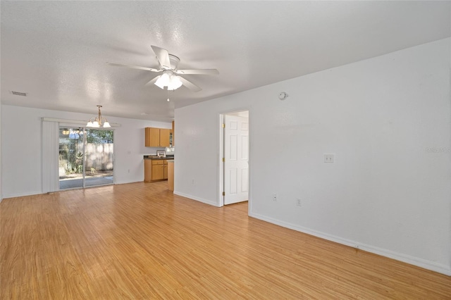 unfurnished living room featuring ceiling fan with notable chandelier, light wood-type flooring, and a textured ceiling