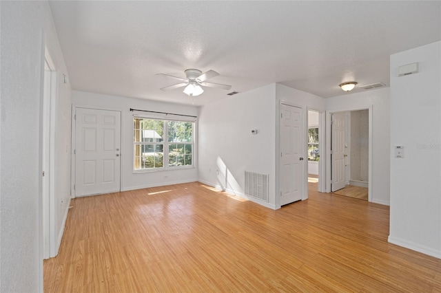 spare room with ceiling fan, light wood-type flooring, and a textured ceiling