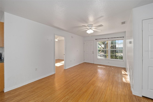 empty room featuring ceiling fan, light wood-type flooring, and a textured ceiling