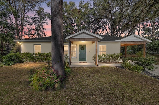 ranch-style house featuring a carport and a yard