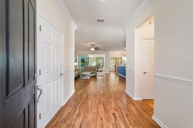 hallway with ornamental molding and light wood-type flooring