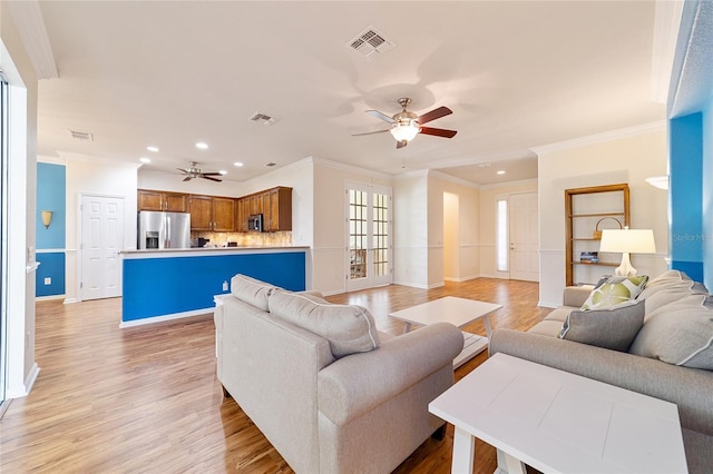 living room with light hardwood / wood-style floors, ceiling fan, and ornamental molding