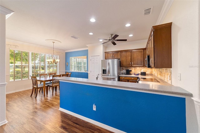 kitchen with dark hardwood / wood-style flooring, ornamental molding, ceiling fan with notable chandelier, stainless steel appliances, and decorative light fixtures