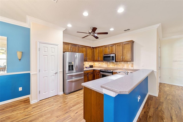 kitchen featuring kitchen peninsula, appliances with stainless steel finishes, light wood-type flooring, ceiling fan, and sink