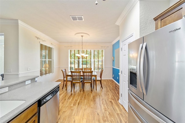 kitchen with pendant lighting, crown molding, a notable chandelier, light hardwood / wood-style floors, and stainless steel appliances