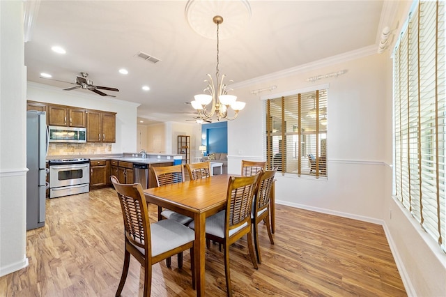 dining area with ceiling fan with notable chandelier, light wood-type flooring, and crown molding