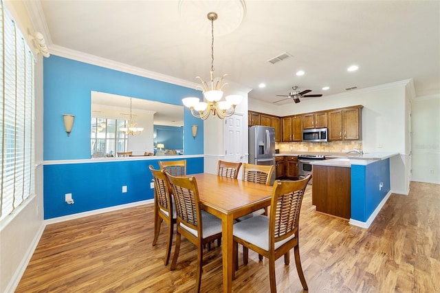 dining room featuring hardwood / wood-style floors, ceiling fan with notable chandelier, and crown molding