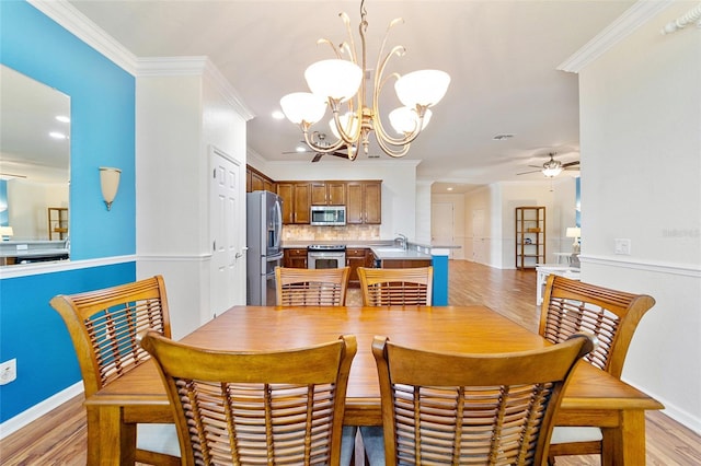 dining area with ceiling fan with notable chandelier, light hardwood / wood-style floors, crown molding, and sink