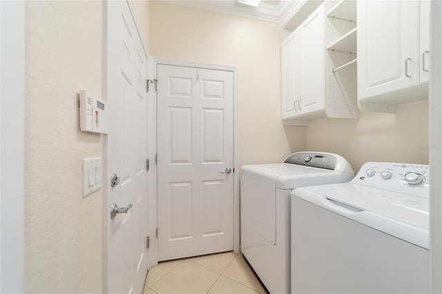 laundry room featuring cabinets, washing machine and dryer, light tile patterned floors, and crown molding