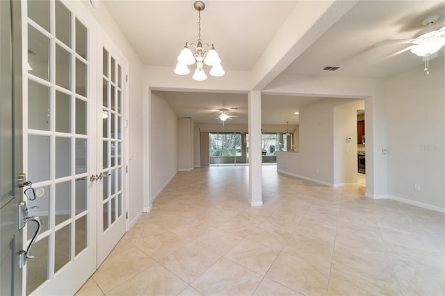 unfurnished room with french doors, light tile patterned floors, and ceiling fan with notable chandelier