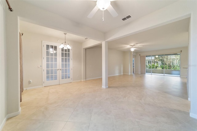 spare room featuring french doors and ceiling fan with notable chandelier