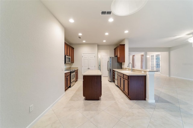 kitchen featuring ceiling fan, sink, kitchen peninsula, a kitchen island, and appliances with stainless steel finishes