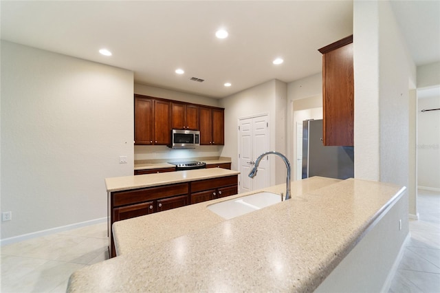 kitchen with light stone countertops, a center island, sink, light tile patterned flooring, and appliances with stainless steel finishes