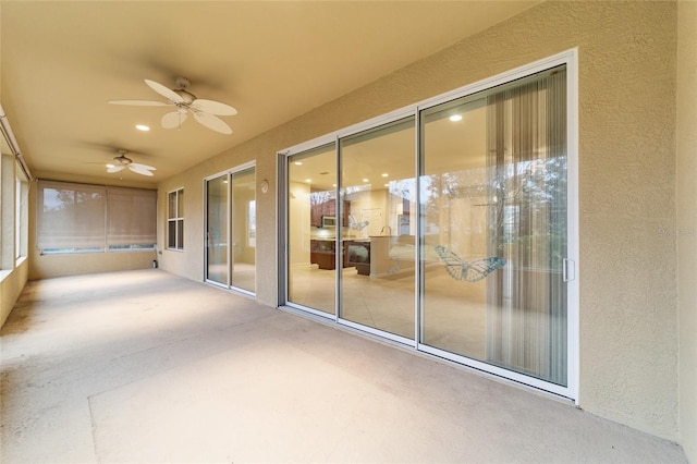 unfurnished sunroom featuring ceiling fan