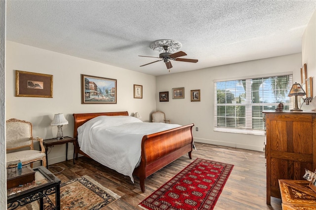 bedroom with hardwood / wood-style floors, a textured ceiling, and ceiling fan