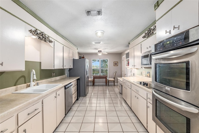 kitchen featuring white cabinetry, sink, stainless steel appliances, a textured ceiling, and light tile patterned floors