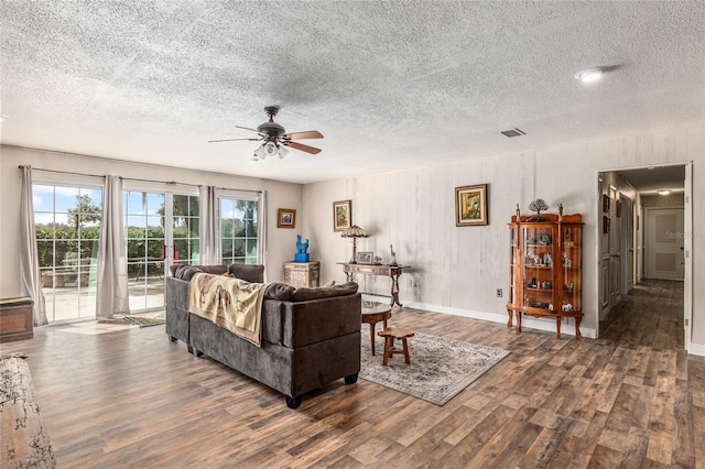 living room featuring ceiling fan, dark hardwood / wood-style floors, and a textured ceiling