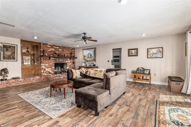 living room with a fireplace, hardwood / wood-style floors, a textured ceiling, and ceiling fan