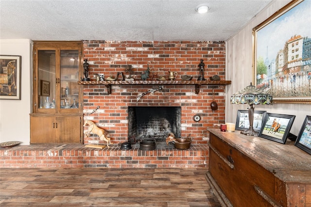 interior space with hardwood / wood-style flooring, a textured ceiling, and a brick fireplace