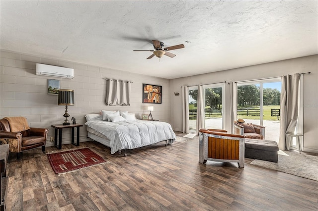 bedroom with ceiling fan, dark hardwood / wood-style floors, access to exterior, a textured ceiling, and a wall unit AC