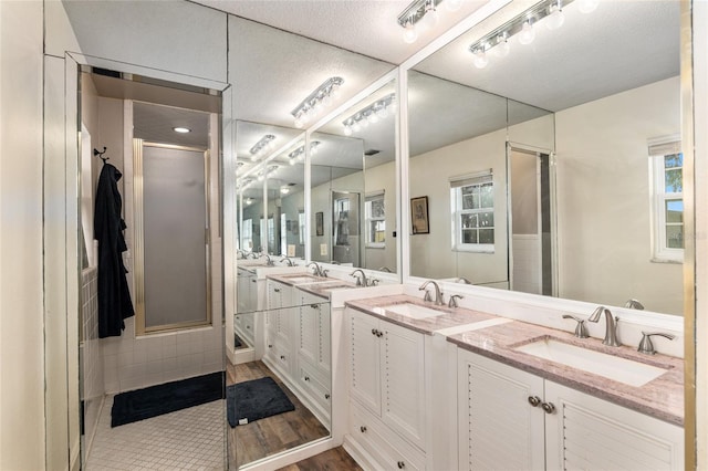 bathroom featuring tile patterned flooring, a textured ceiling, vanity, and a shower with door