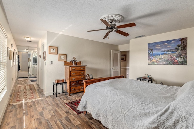 bedroom with ceiling fan, hardwood / wood-style floors, and a textured ceiling