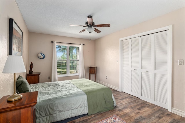 bedroom with ceiling fan, dark hardwood / wood-style floors, a textured ceiling, and a closet