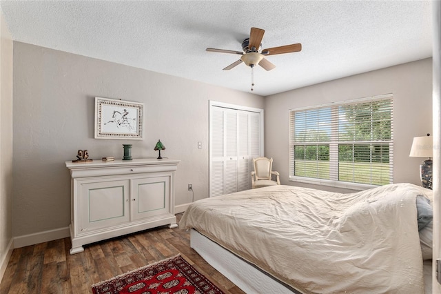 bedroom with a textured ceiling, a closet, ceiling fan, and dark wood-type flooring