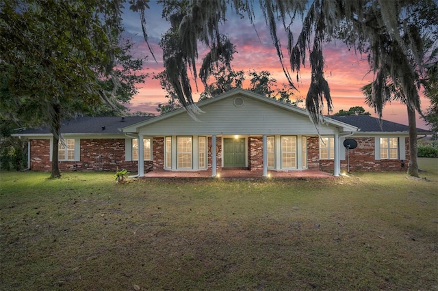 back house at dusk featuring a yard