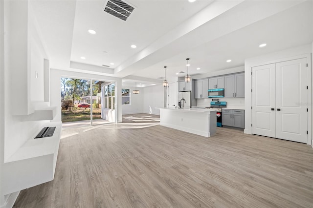 unfurnished living room featuring ceiling fan, light hardwood / wood-style floors, a raised ceiling, and sink