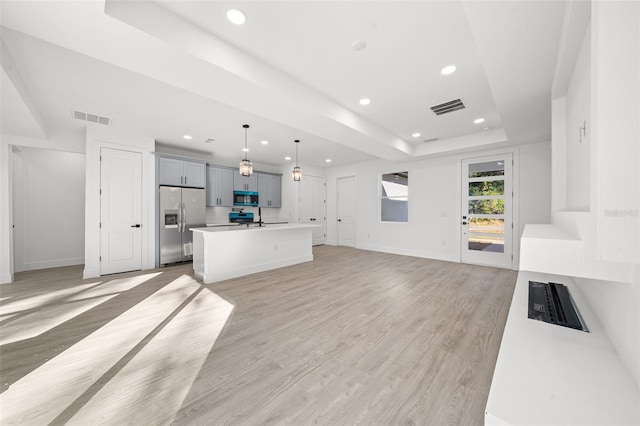 living room with a raised ceiling, sink, and light hardwood / wood-style floors