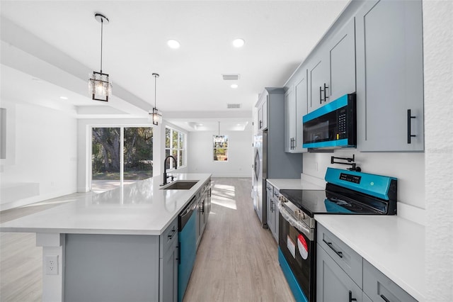 kitchen featuring gray cabinetry, sink, light hardwood / wood-style floors, a kitchen island with sink, and appliances with stainless steel finishes