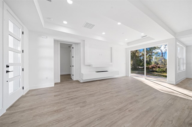 unfurnished living room with a tray ceiling and light hardwood / wood-style flooring