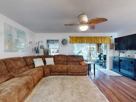 living room featuring hardwood / wood-style floors, ceiling fan, and a fireplace