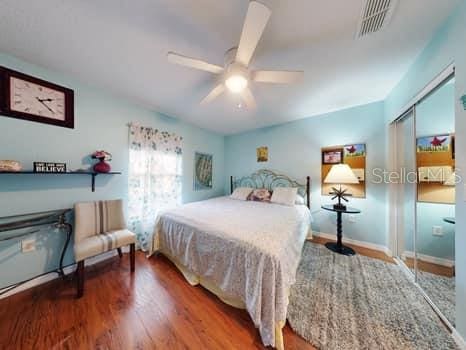 bedroom with ceiling fan, wood-type flooring, and a closet