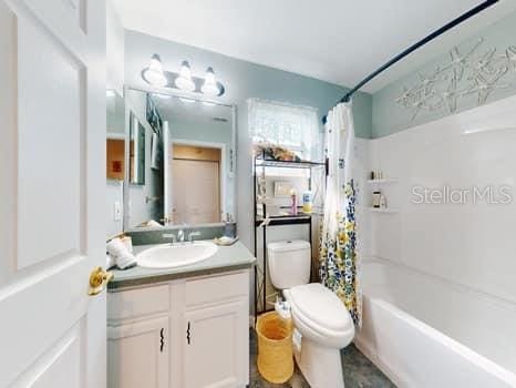 full bathroom with shower / bath combination with curtain, toilet, and vanity