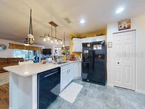 kitchen featuring black appliances, white cabinets, sink, decorative light fixtures, and kitchen peninsula