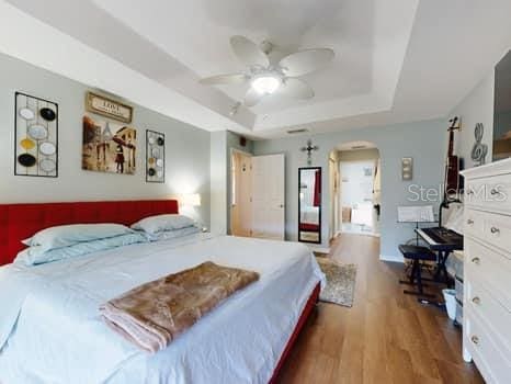 bedroom featuring a raised ceiling, ceiling fan, and dark hardwood / wood-style flooring