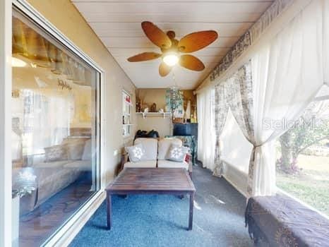 interior space with ceiling fan and dark colored carpet