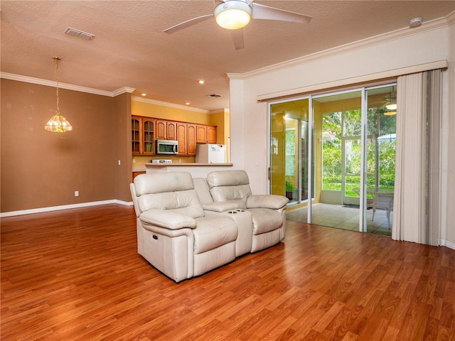 living room featuring ceiling fan, light hardwood / wood-style floors, ornamental molding, and a textured ceiling