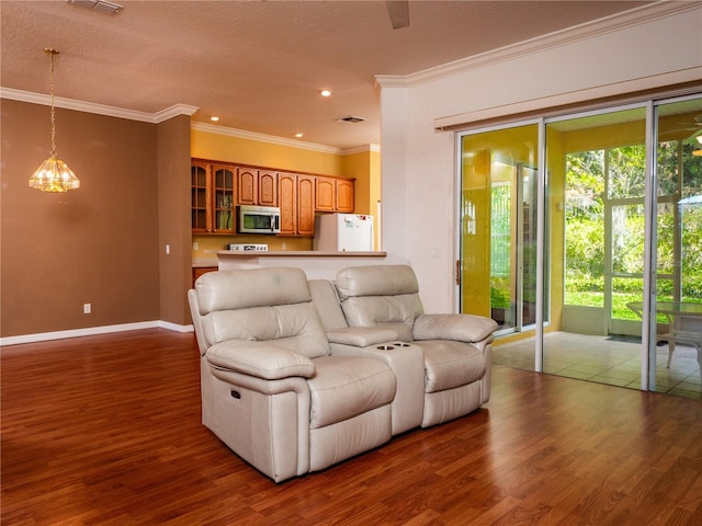 living room with a notable chandelier, dark hardwood / wood-style flooring, ornamental molding, and a textured ceiling