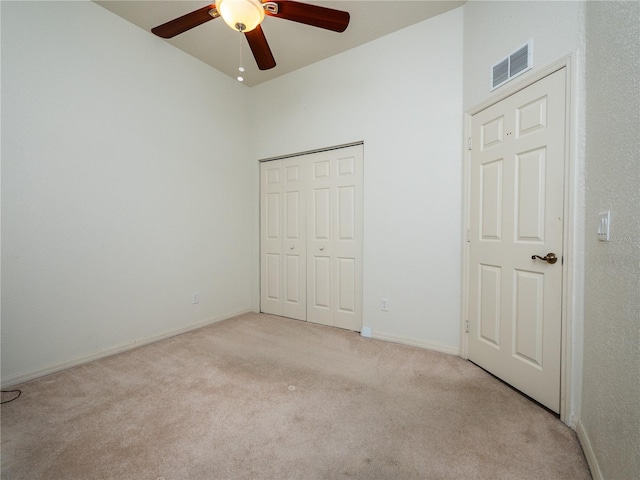 unfurnished bedroom featuring a closet, light colored carpet, and ceiling fan